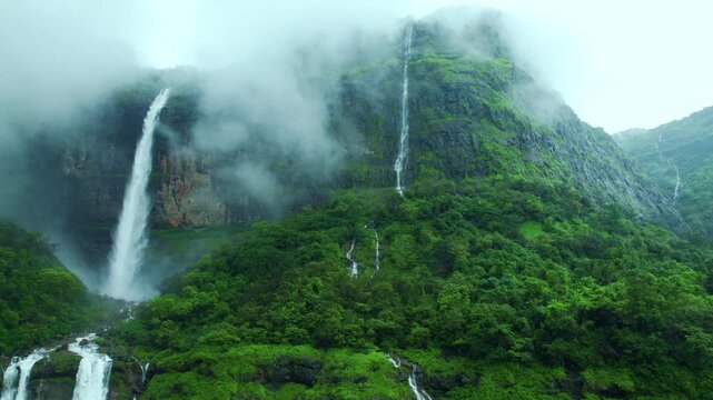 4K Aerial view of Nanemachi waterfall falling from the cliff surrounded by monsoon clouds during the rainy season at Raigad District in Maharashtra, India. Monsoon in Sahyadri range background.