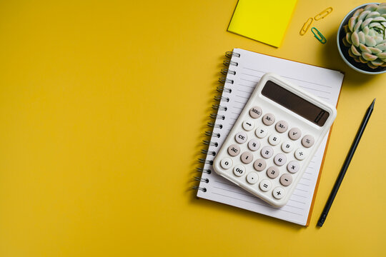 Business financial analysis with calculator and notebook on yellow background, flat lay with copy space