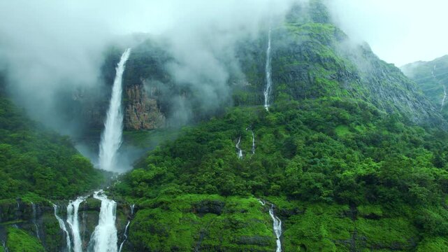 4K Aerial shot of Nanemachi waterfall in the western Ghats during monsoon at Maharashtra, India. Surrounded by lush green mountains, misty clouds and cascading streams. Beauty of nature. Travel concep