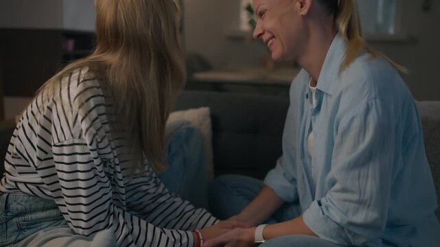 Mother and teenage daughter laughing and talking together at home, showing emotional wellbeing, positive family communication, trust and supportive parenting during adolescence.