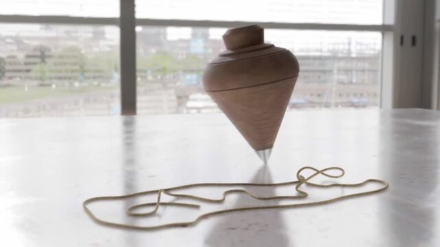 Wooden spinning top toy with string on a marble surface indoors