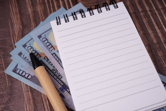 Blank notebook and Malaysian ringgit banknotes on a wooden desk, representing financial planning, budgeting, savings, and business ideas.