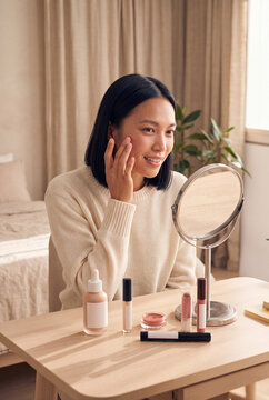 Woman applying makeup at vanity mirror with brushes and cosmetics for natural everyday beauty routine and portrait banner