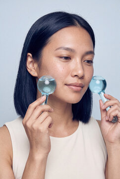 Woman using glass facial globes for facial massage and cooling skincare routine for antiaging and beauty care visuals