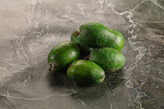 Green feijoas on dark marble surface