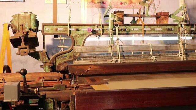 A traditional mechanical loom (power loom) sits idle inside a textile studio or workshop. 