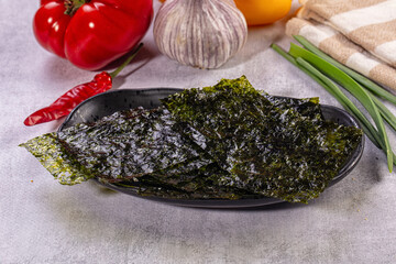 Nori seaweed sheets on dark plate with fresh vegetables © Andrei Starostin