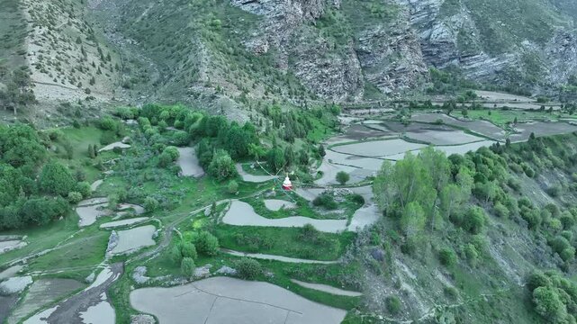 Aerial view of village in mountains with farm terraces colorful houses and winding mountain roads . Shot by a drone flying over