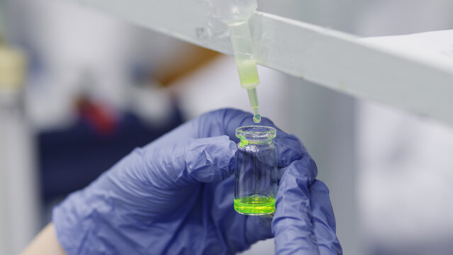 Drop filtration of green luminescent protein in liquid and collection in a glass vial.