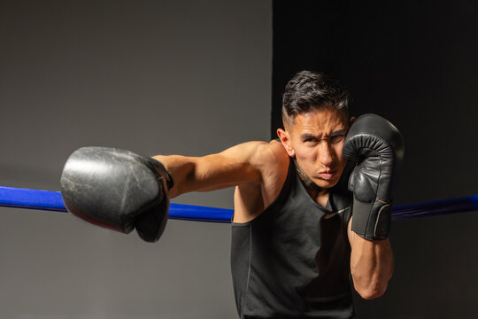 Powerful Hispanic boxer throwing punch with intense expression in ring
