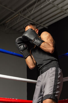 Hispanic boxer protecting face with gloves in defensive stance in ring