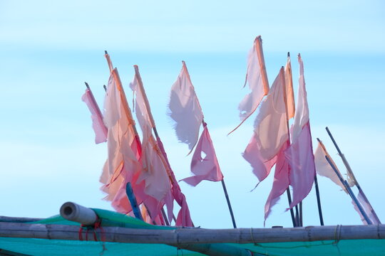 Tattered pink and white flags fluttering in wind against blue sky background coastal marine marker pennants
