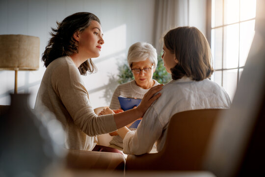 Supportive Group Therapy Session in Sunlit Room with Three Women Sharing Emotions