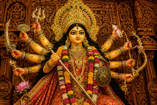 Goddess Durga idol with multiple symbolic weapons and floral garland in ornate festive temple artwork