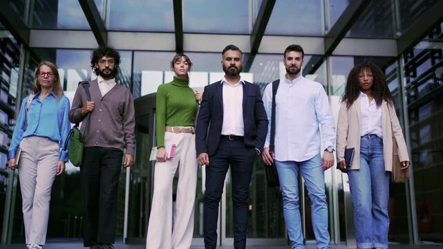 Confident multicultural group of professionals looking at the camera in front of a modern building. 