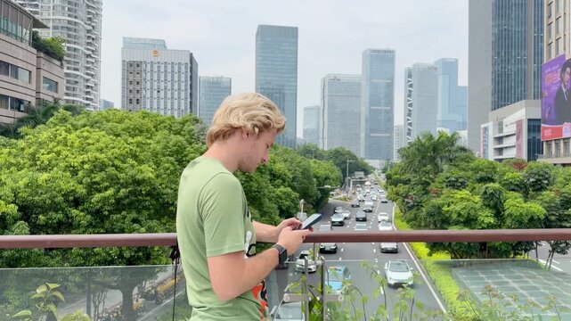 Young Man Using Smartphone Against Skyscrapers &ndash; Talking, Scrolling or Recording Video