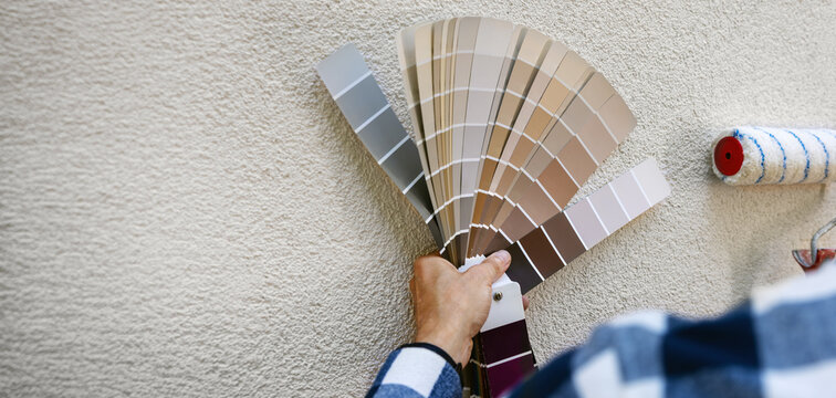man choosing paint color from samples palette for house stucco plaster exterior. copy space