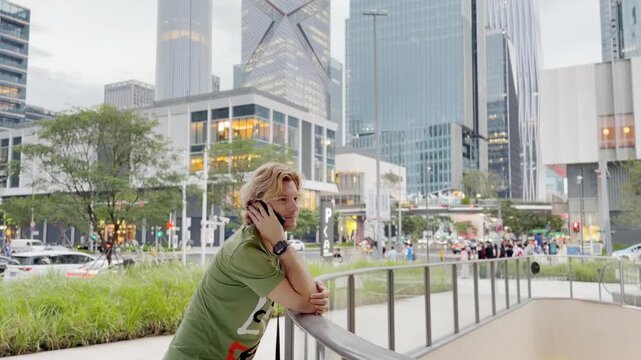 Young Man Using Smartphone Against Skyscrapers &ndash; Talking, Scrolling or Recording Video