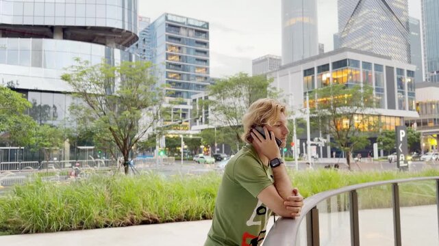 Young Man Using Smartphone Against Skyscrapers &ndash; Talking, Scrolling or Recording Video