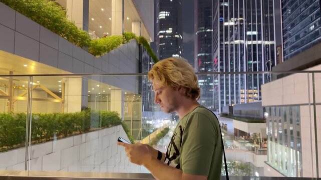 Young Man Using Smartphone Against Skyscrapers &ndash; Talking, Scrolling or Recording Video