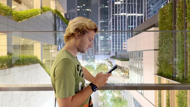 Young Man Using Smartphone Against Skyscrapers &ndash; Talking, Scrolling or Recording Video