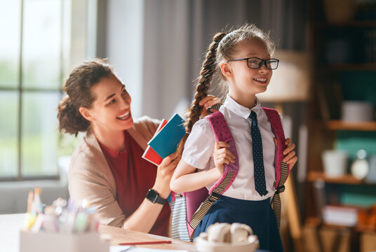 Happy mother getting daughter ready for school with backpack