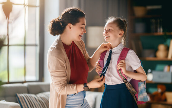 Happy Mother Helping Daughter Get Ready for School at Home in Morning Light