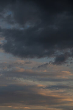 Dramatic storm clouds at sunset creating a moody dark sky with warm evening light