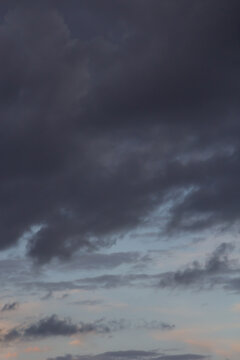 Dramatic dark storm clouds rolling across the dusk sky with moody blue and gray tones