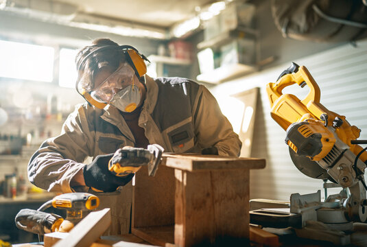 Skilled Carpenter Wearing Safety Gear Working with Wood in Works