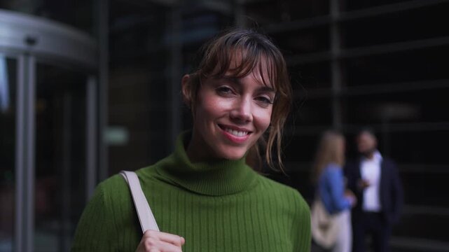 Portrait of a happy professional woman looking at the camera cheerfully, in front of a modern business center.