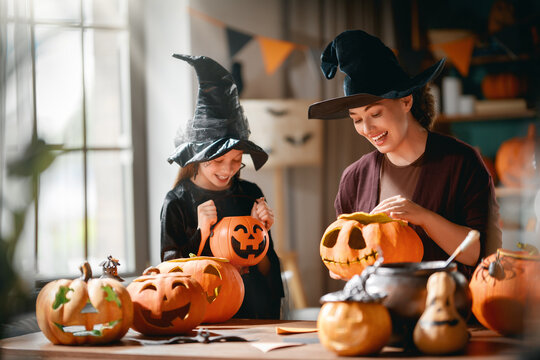 Happy Family Carving Pumpkins for Halloween Celebration at Home in Witch Costumes