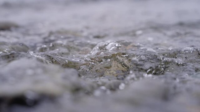 Geothermal water, Gunnuhver, Reykjanesbaer, Southern Peninsula, Iceland, flowing over mineral-coated volcanic ground with vigorous bubbling and hydrothermal activity, static close-up.