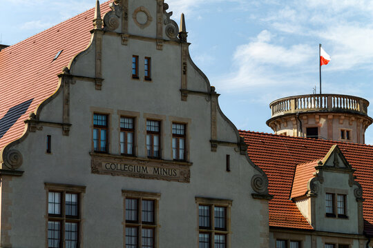 Horizontal city architecture photo of historic Collegium Minus Uniwersytet im. Adama Mickiewicza building with Polish flag in Poznan, Poland
