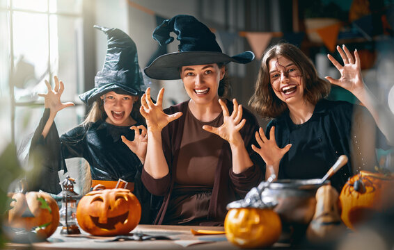 Happy Family in Witch Costumes Celebrating Halloween with Pumpkins