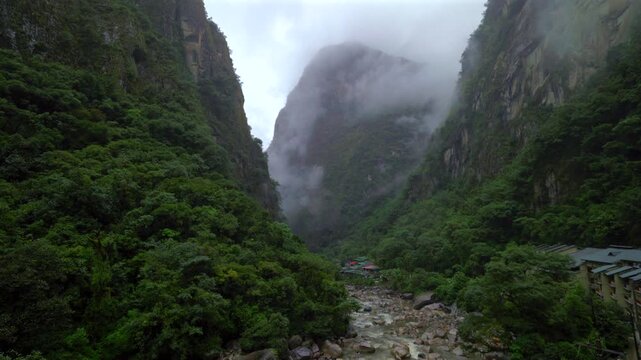 Machu Picchu entrance Aguas Calientes town Amazon Urabumba river dry rainy season misty clouds Peru jungle hillside Peruvian Andes Mountains lower highlands Inca trail citadel hotels landscape static