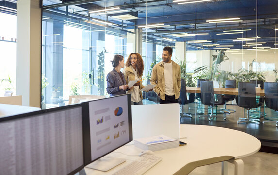 Team colleagues in office meeting discussion. They plan a presentation by the conference room as charts on screens highlight strategy, goals and workflow. Clear teamwork and planning concept.