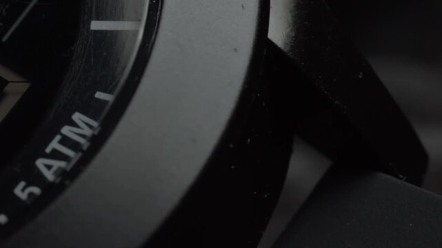 Panning shot of digital wristwatch display showing illuminated numbers, highlighting segmented digits, dark watch surface, and electronic time display in close-up