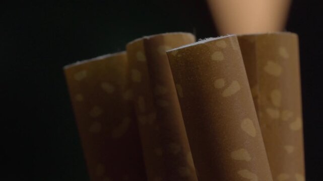 Panning shot moves across brown cigars, revealing natural leaf patterns, smooth rolled surfaces, cylindrical shapes, and fine texture under warm light