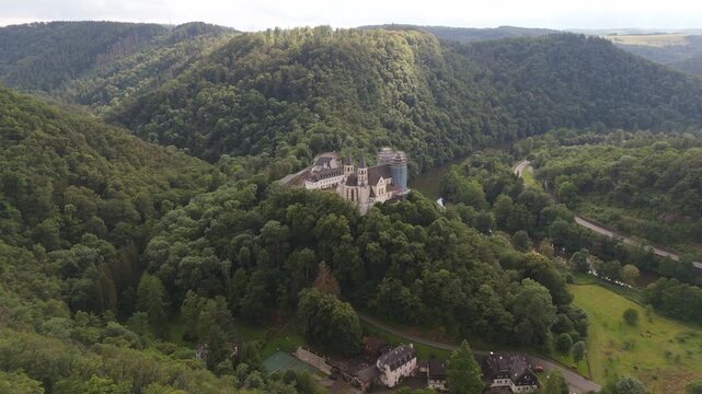 Aerial drone pan left tracking shot over monastery Arnstein, and the lush mountain valleys along the Lahn river in Rhineland-Palatinate, Germany.