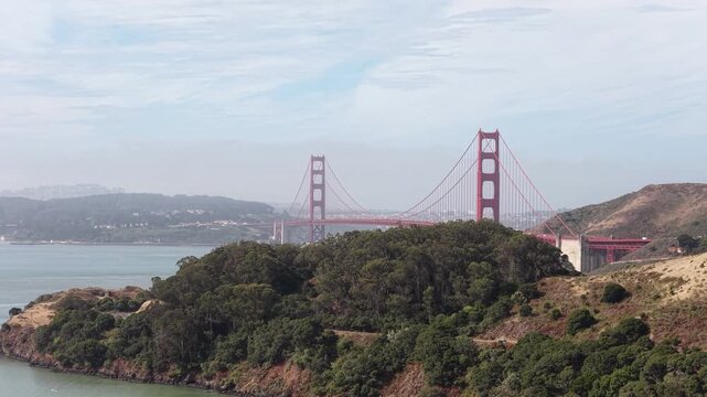 An aerial perspective from Sausalito showcases the Golden Gate Bridge against San Francisco Bay, highlighting its distinctive architecture, surrounding hills, shoreline, and connection to the city