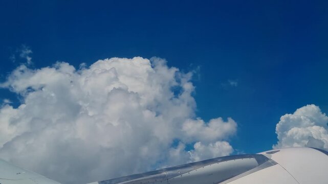 Passenger view above Argentina, flying through white clouds beneath a clear blue sky, with gentle turbulence creating an authentic air travel experience