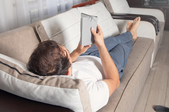 Caucasian man reading book at home.