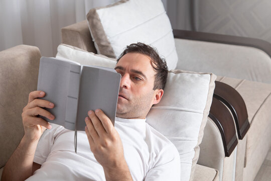 Caucasian man reading book at home.