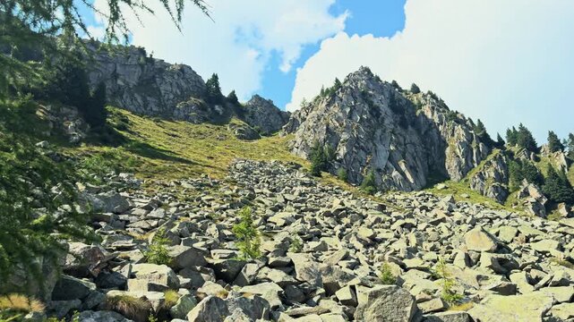 Rocky slope of a mountain in the adamello brenta nature park. A sunny summer day in the italian alps with a blue sky and white clouds