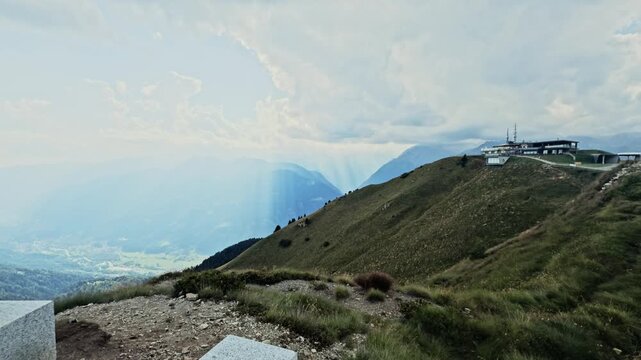 Stunning mountain view from malga cioca, with doss del sabion and the valley below. Sun rays are filtering through the clouds over pinzolo