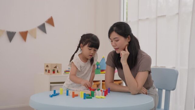 Mother Daughter Child Family Playing Colorful Wooden Block Toy Learning Activity at Home, Focused Educational Game, Building Creative Structure Together Beside Bright Window with Joyful Interaction