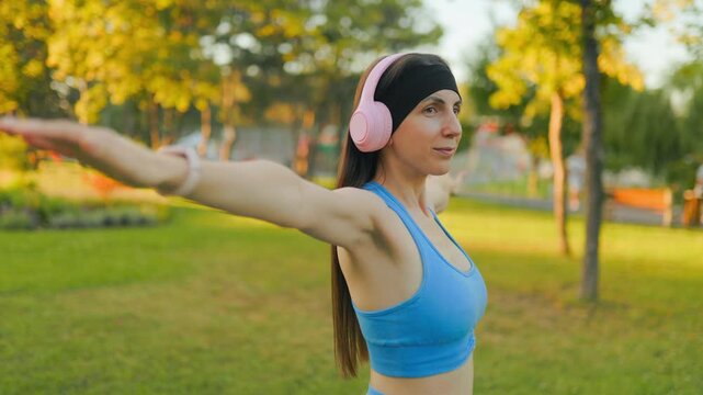 Side view of a fit woman practicing arm stretching exercise in the sunny park.