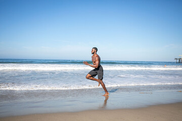 Fototapeta premium Man jogging along sandy beach.