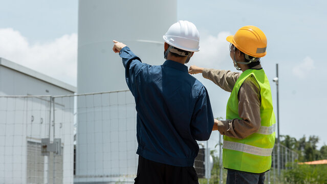 Engineers Inspecting Wind Turbine Substation Structure and Pointing Up